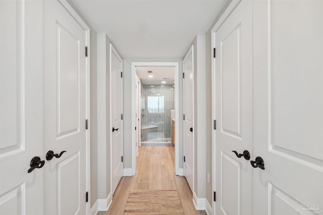 hall with light wood-type flooring and baseboards