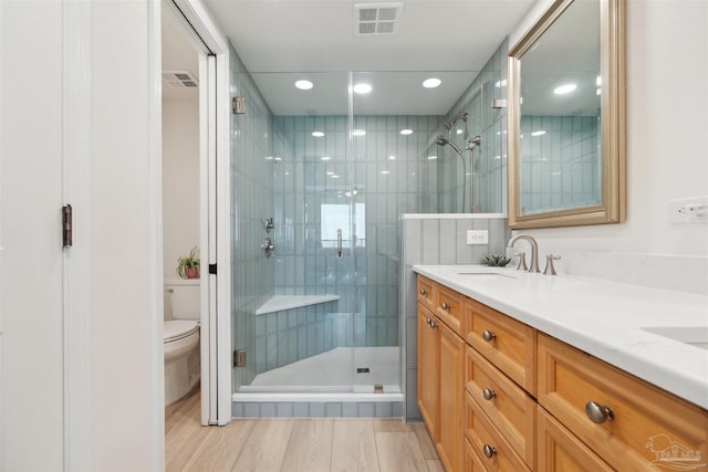 full bathroom with recessed lighting, a shower stall, visible vents, toilet, and a sink
