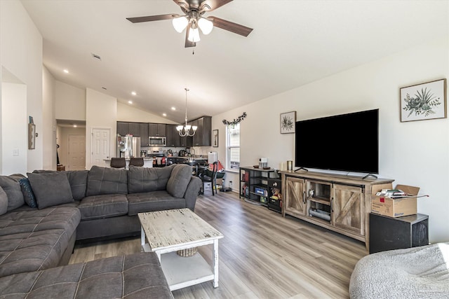 living room with light hardwood / wood-style floors, high vaulted ceiling, and ceiling fan with notable chandelier