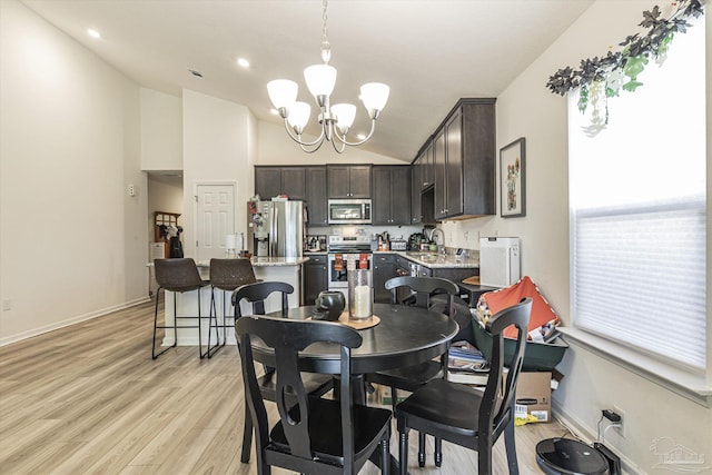 dining area featuring sink, high vaulted ceiling, a notable chandelier, and light hardwood / wood-style flooring