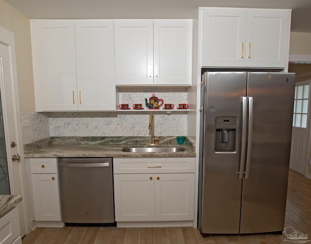 kitchen featuring a sink, tasteful backsplash, stainless steel appliances, and white cabinetry