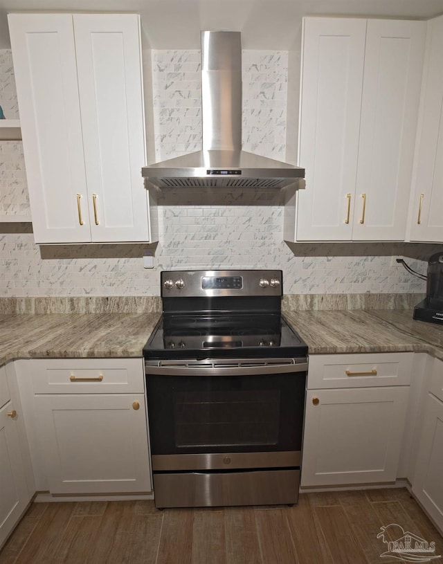 kitchen featuring wall chimney range hood, white cabinetry, decorative backsplash, and electric stove