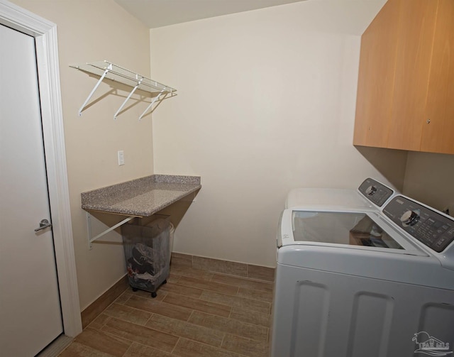 washroom with washer and dryer, wood finish floors, and cabinet space