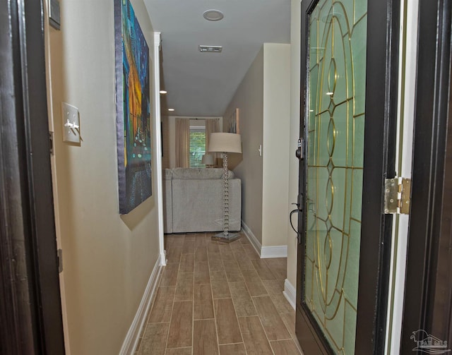foyer entrance featuring baseboards, visible vents, and wood finished floors