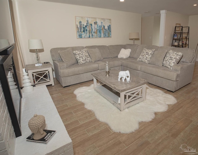 living area with light wood-style floors, recessed lighting, and decorative columns