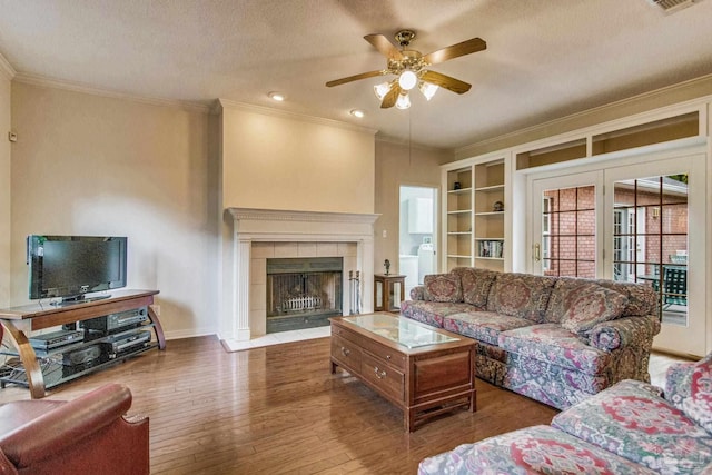 living room featuring a textured ceiling, ceiling fan, crown molding, a fireplace, and dark hardwood / wood-style floors