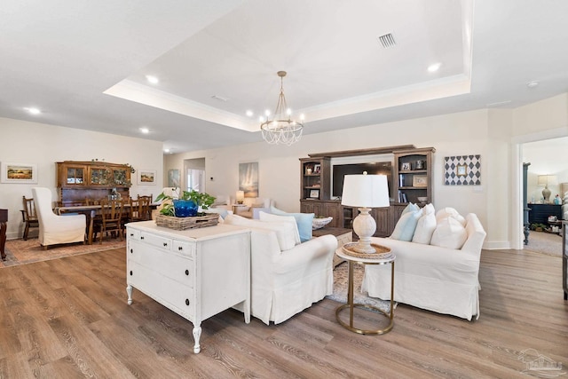 living room featuring a raised ceiling, wood-type flooring, and an inviting chandelier