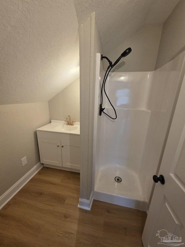 5674 Windsong Dr, Milton, FL 32570 - full bathroom with lofted ceiling, a textured ceiling, wood finished floors, a shower stall, and baseboards