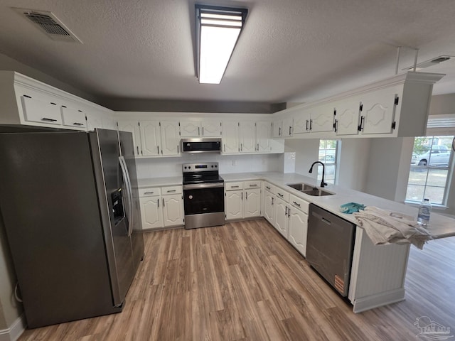 5674 Windsong Dr, Milton, FL 32570 - kitchen with stainless steel appliances, a peninsula, light wood-type flooring, a sink, and light countertops