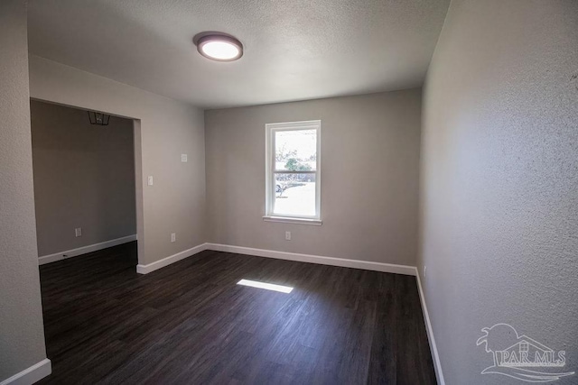 unfurnished room featuring a textured ceiling and dark hardwood / wood-style floors