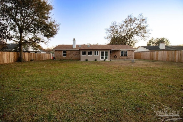 back house at dusk featuring a lawn