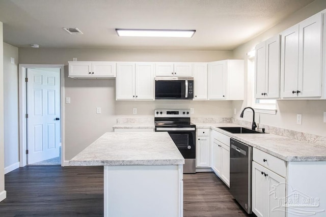 kitchen featuring appliances with stainless steel finishes, white cabinetry, a kitchen island, and sink