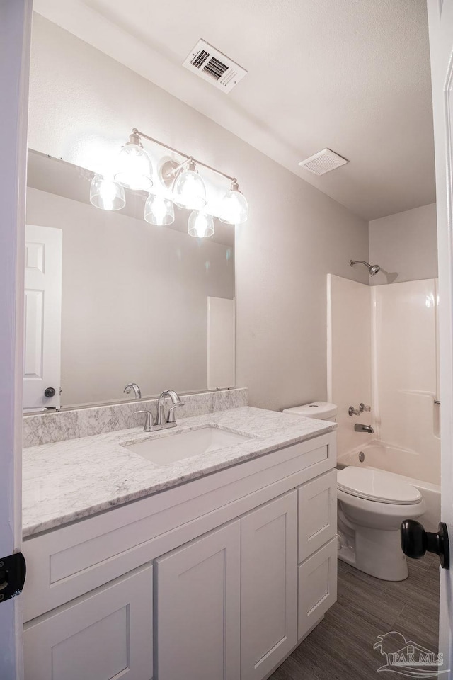 full bathroom featuring hardwood / wood-style floors, vanity, shower / bath combination, and toilet