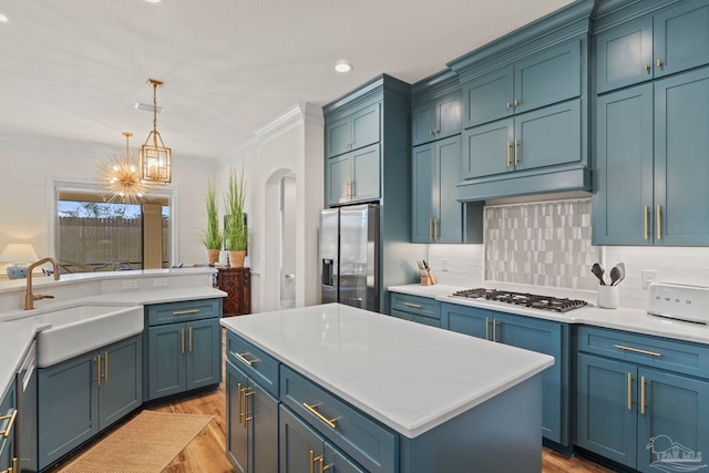 kitchen featuring hanging light fixtures, appliances with stainless steel finishes, a sink, and blue cabinets