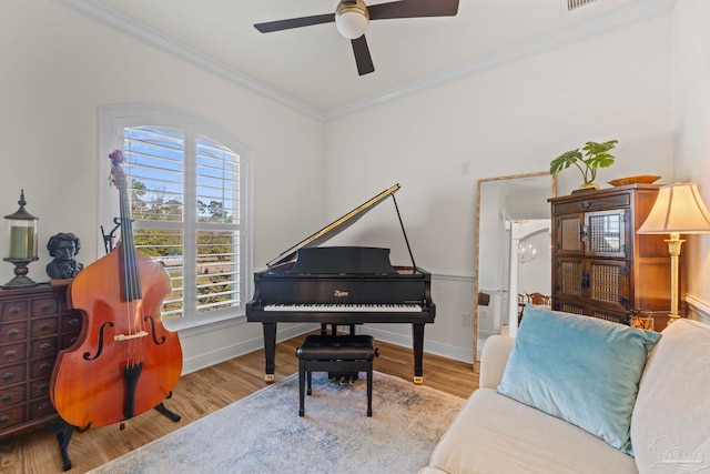 sitting room with ornamental molding, light wood-type flooring, and baseboards