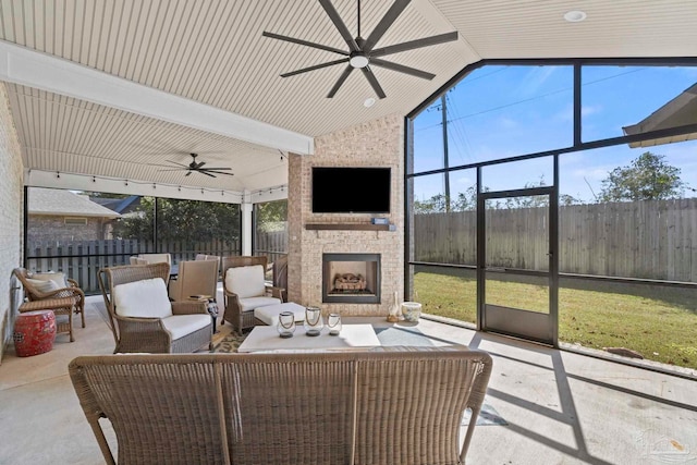 sunroom featuring lofted ceiling, an outdoor stone fireplace, and ceiling fan