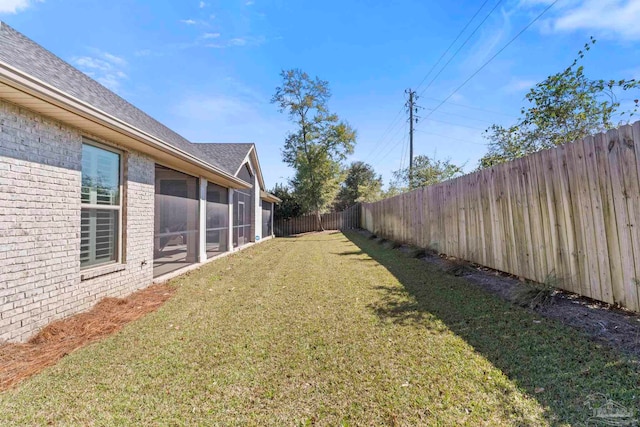 view of yard featuring a sunroom and a fenced backyard