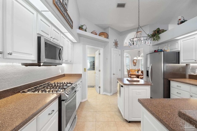 kitchen with stainless steel appliances, white cabinets, decorative light fixtures, a kitchen island, and light tile patterned flooring