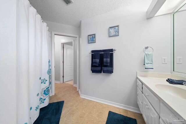 bathroom featuring vanity, toilet, tile patterned floors, and a textured ceiling