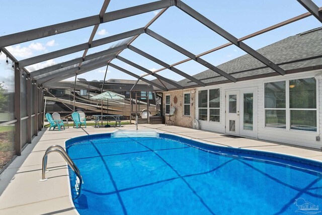 view of swimming pool featuring a patio area, a diving board, and glass enclosure