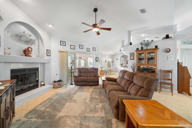 living room with tile patterned floors, a tile fireplace, ceiling fan, and high vaulted ceiling