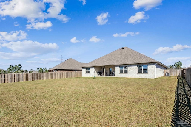 back of property with a yard, a fenced backyard, roof with shingles, and brick siding