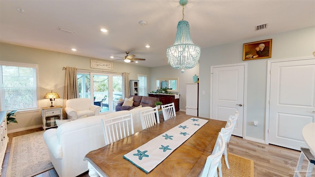 dining area with ceiling fan with notable chandelier and light hardwood / wood-style flooring