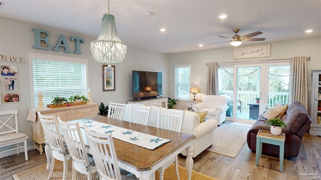 dining room featuring ceiling fan with notable chandelier and light hardwood / wood-style floors