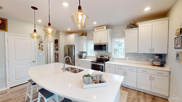 kitchen with decorative light fixtures, decorative backsplash, sink, stainless steel appliances, and white cabinets