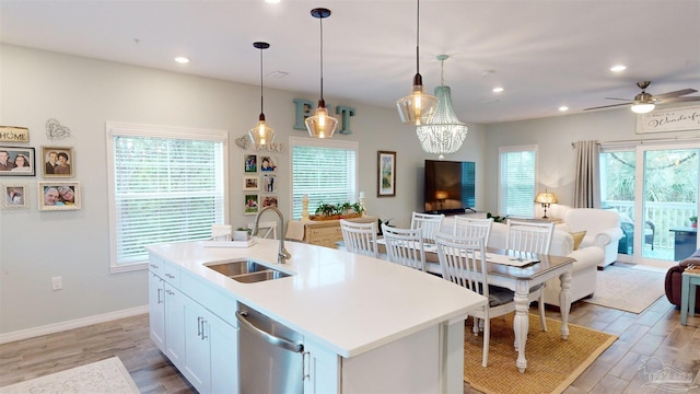 kitchen with dishwasher, sink, hanging light fixtures, an island with sink, and white cabinets