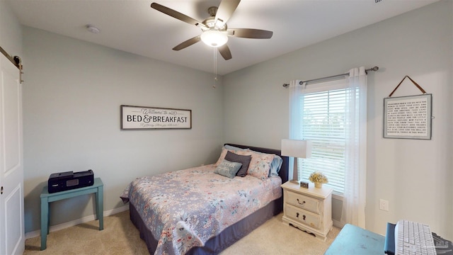 bedroom featuring ceiling fan, light colored carpet, and a barn door