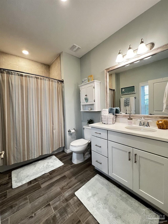 bathroom with wood-type flooring, toilet, vanity, and walk in shower