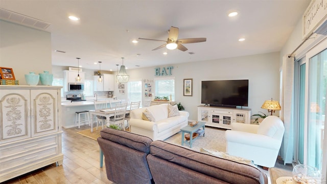 living room featuring ceiling fan and light hardwood / wood-style floors