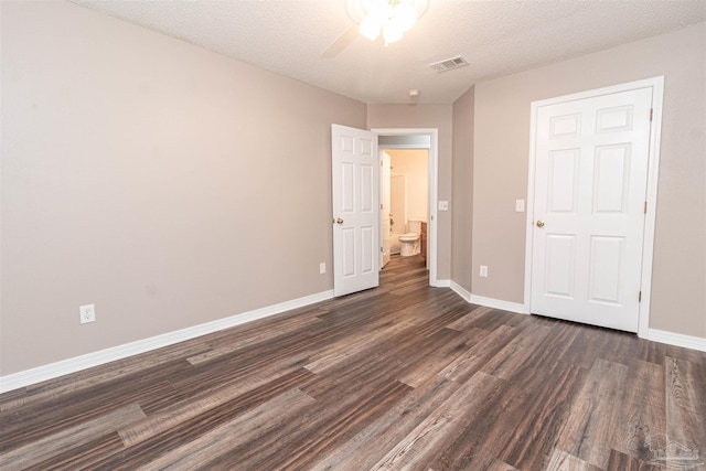 unfurnished bedroom featuring dark wood-style floors, baseboards, a textured ceiling, and ceiling fan