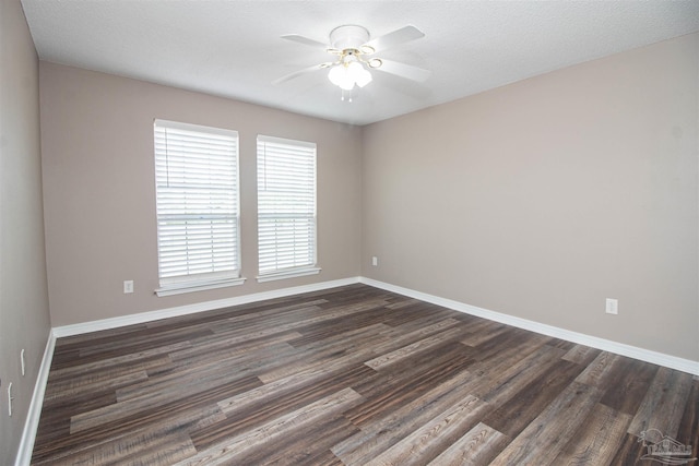 spare room with ceiling fan, dark wood-style flooring, and baseboards