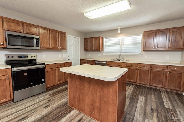 kitchen featuring appliances with stainless steel finishes, a sink, dark wood finished floors, light countertops, and a textured ceiling