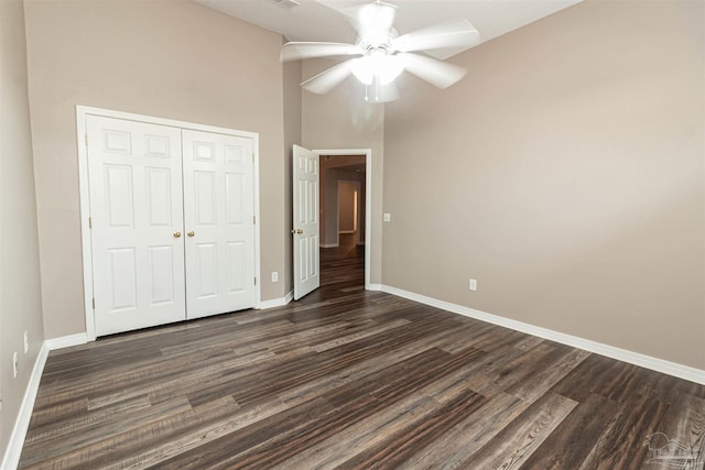 unfurnished bedroom with baseboards, a closet, dark wood-style flooring, and ceiling fan