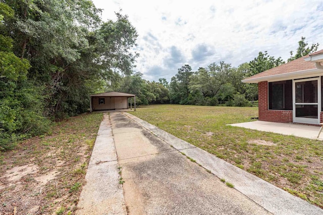 view of grassy yard with concrete driveway and a carport