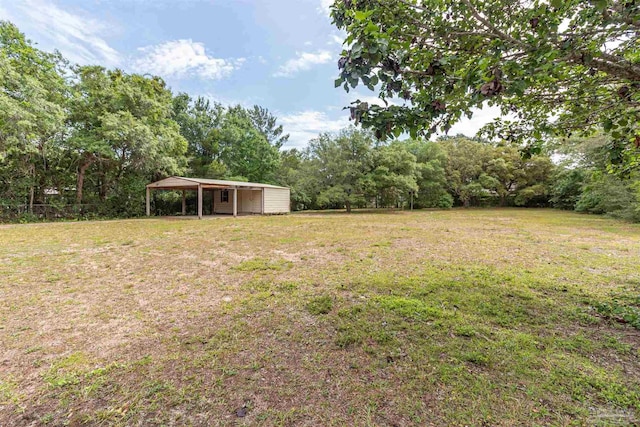 view of green lawn featuring a carport and an outbuilding