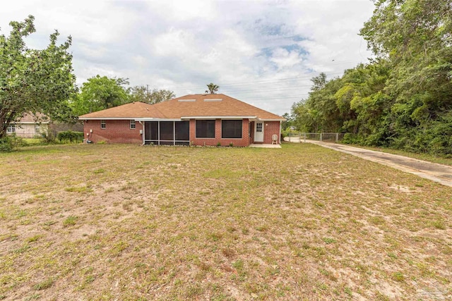 rear view of property featuring a sunroom, brick siding, and driveway