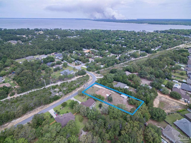 aerial view of property and surrounding area with a nearby body of water, property parcel outlined, and nearby suburban area