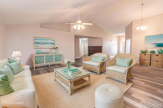 living area featuring wood finished floors, vaulted ceiling, a ceiling fan, baseboards, and a chandelier