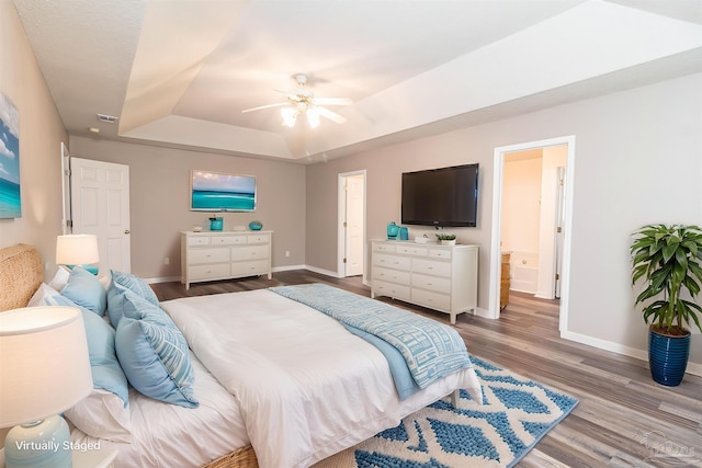 bedroom featuring a raised ceiling, baseboards, wood finished floors, and a ceiling fan