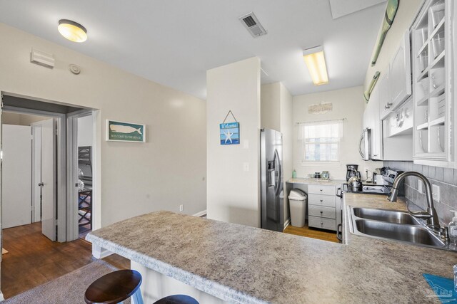 kitchen with white cabinets, sink, appliances with stainless steel finishes, dark hardwood / wood-style flooring, and kitchen peninsula