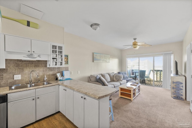 kitchen featuring dishwasher, white cabinets, sink, carpet flooring, and kitchen peninsula