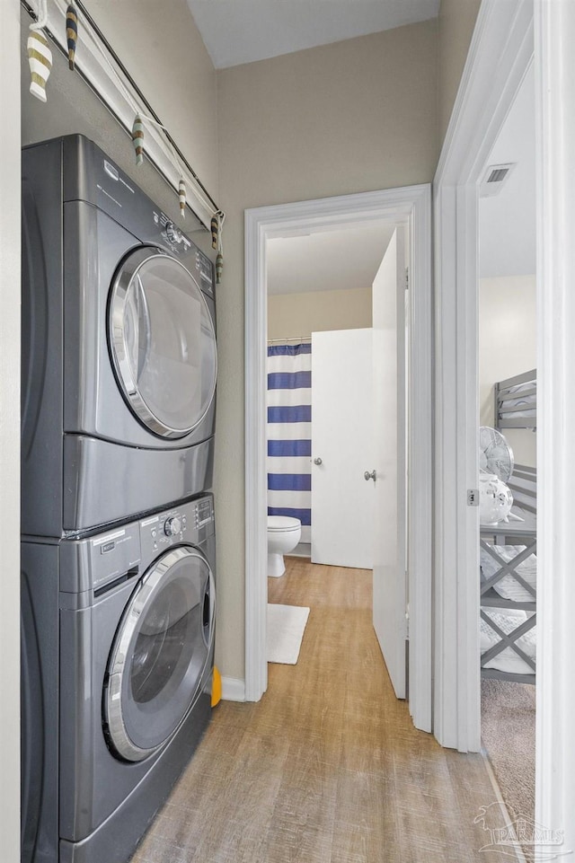 laundry area with light colored carpet and stacked washer / dryer