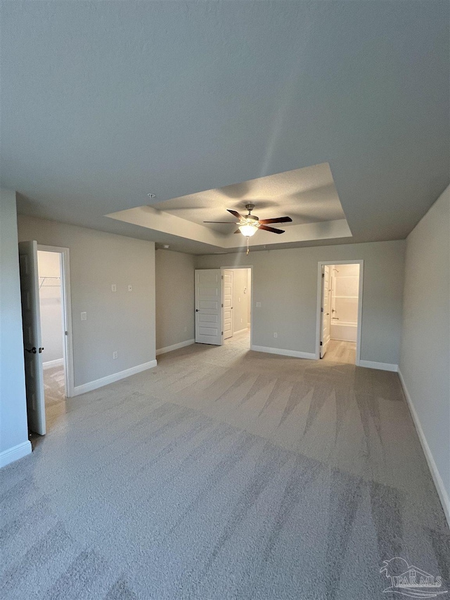 spare room featuring ceiling fan, light colored carpet, and a raised ceiling