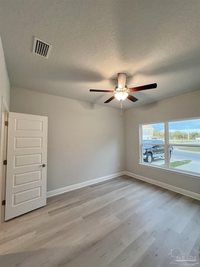 empty room featuring a textured ceiling and light wood-type flooring