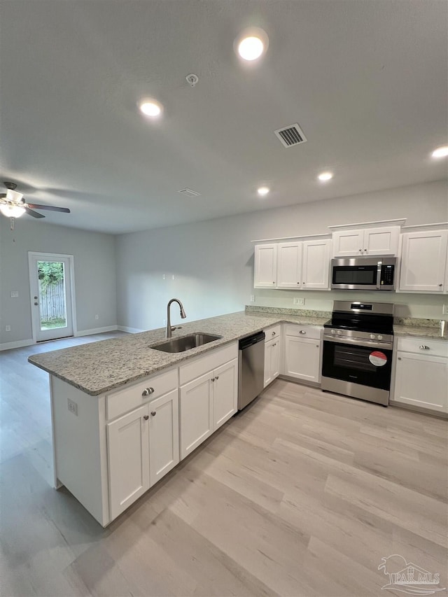 kitchen with white cabinetry, sink, kitchen peninsula, stainless steel appliances, and light stone countertops