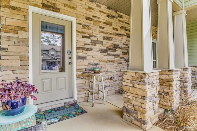 view of exterior entry with a porch and stone siding